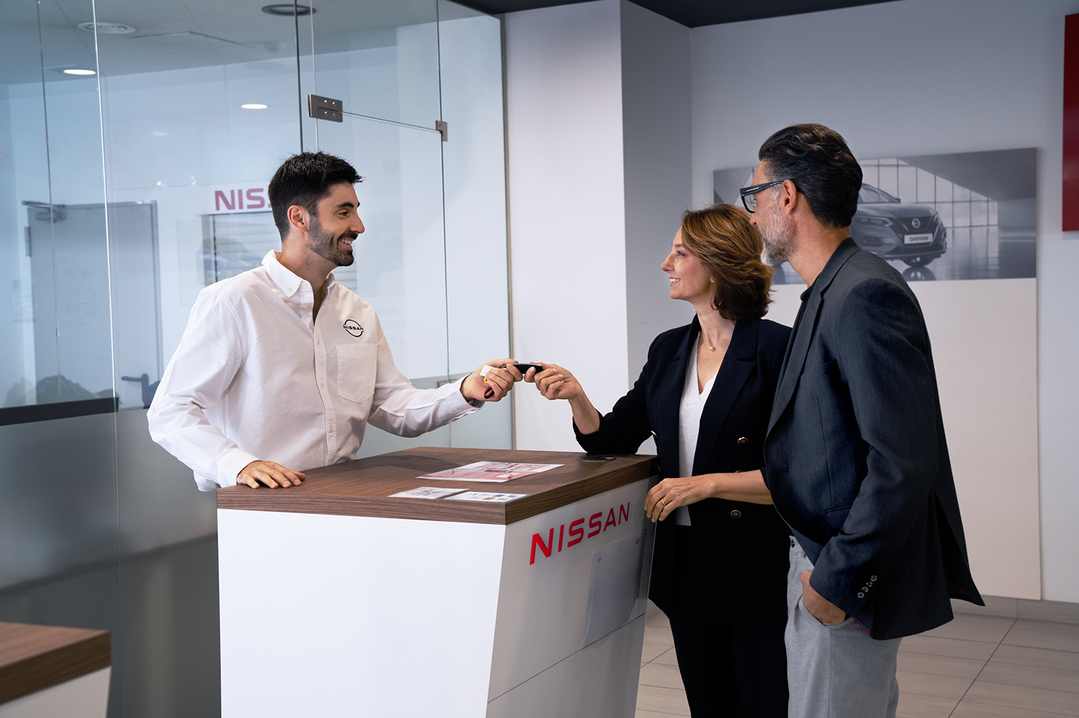 Asesor comercial entregando llaves coche Nissan a una pareja